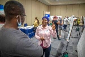 Engaged woman smiling at a conference booth during a professional event.