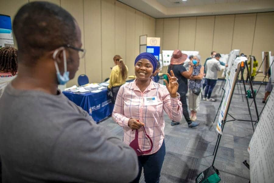 Engaged woman smiling at a conference booth during a professional event.
