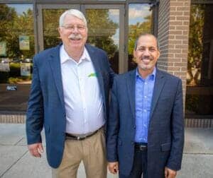 Senior men in business suits smiling outside office building, professional corporate environment, CA.