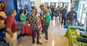CAES News event with attendees networking and exploring informational booths indoors.