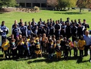 Youth sports team and coaches outdoors on a sunny day in a park setting.