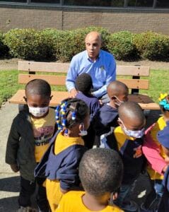 Engaging teacher talking to diverse children outdoors at school playground.