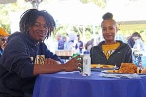 A1. Young adults enjoying outdoor meal at a community event in the park.