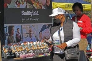 Woman at CAES News booth checking products at outdoor event, promoting responsible food choices.