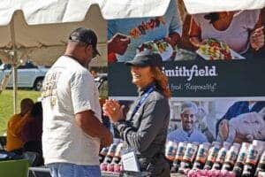 People at a food stall engaging in conversation at an outdoor event.