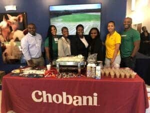 Enjoying a group photo at the Chobani booth during a conference or event.
