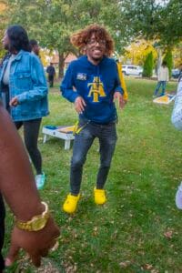 Happy young man dancing outdoors at a park event in casual clothing and yellow Crocs.