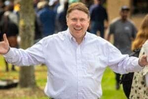 Celebrating outdoors with a smiling man in a white shirt at a community event.