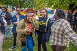 Diverse group of young women smiling outdoors at a community event.