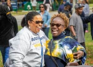 Happy women enjoying outdoor event, smiling and engaging with friends at community gathering.