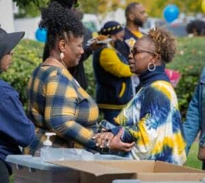 Community members greeting each other at outdoor event in park.