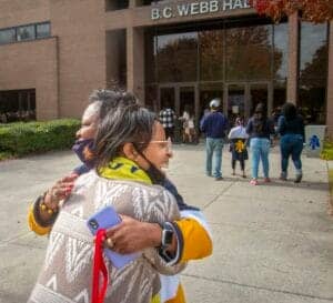 Celebrating school community at B.C. Webb Hall with students and staff embracing outside the buildin.