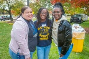 Brightly smiling young women outdoors at a community event, showcasing diversity and engagement in l.