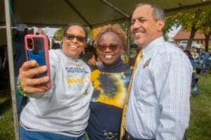 Celebrating community at CAES News event with diverse smiling attendees outdoors.