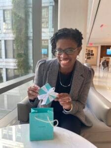 A woman smiling and holding a gift card in a modern indoor setting.
