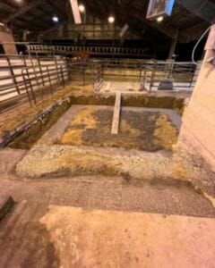 Ancient archaeological excavation site with exposed stone foundations and trenches.