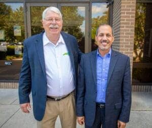 Senior men in business suits smiling outside office building, professional corporate environment, te.