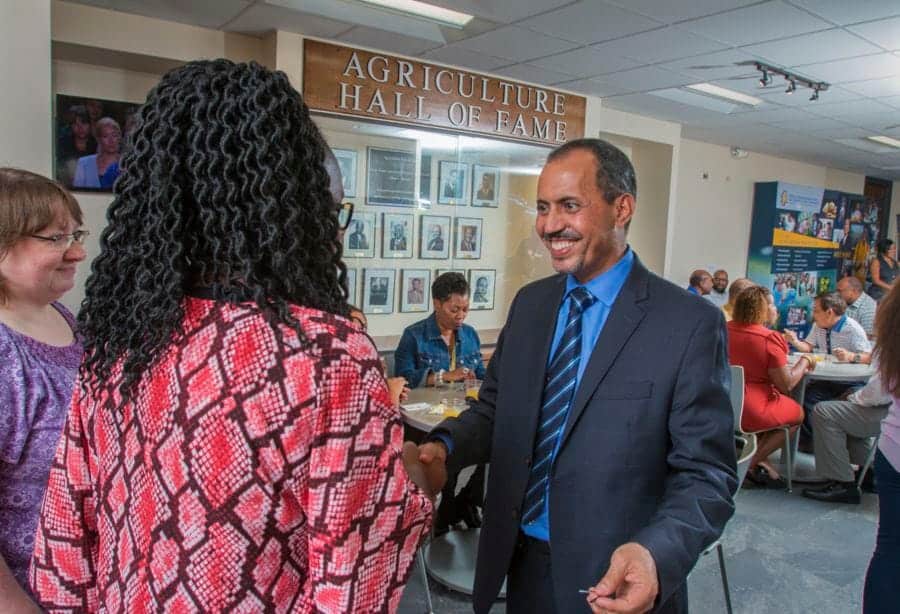 Agriculture Hall of Fame event with people shaking hands and networking indoors.
