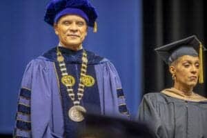 Graduation ceremony with academic regalia and medals at CAES News event.