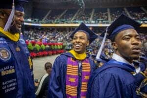 Graduates celebrating at a university commencement ceremony in caps and gowns.