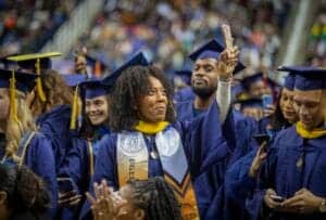 Graduates celebrating at a university commencement ceremony in caps and gowns.