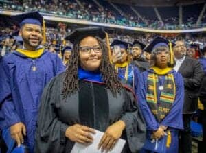 Graduates celebrating at a university graduation ceremony in caps and gowns.
