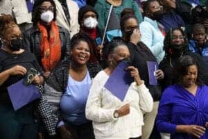 Diverse group of smiling professionals at a conference or seminar, wearing masks and holding documen.