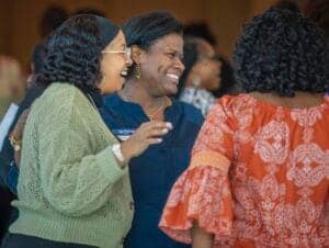 Group of diverse women smiling and engaging in conversation at a professional event.