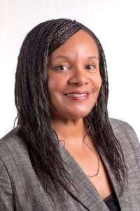 Professional African American woman smiling in business attire for corporate headshot.