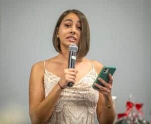 Woman speaking into microphone while using smartphone at event.