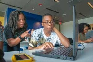 Engaged students collaborating on a laptop in a modern classroom setting.