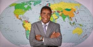 Global businessman standing in front of a world map, representing international news and global conn.