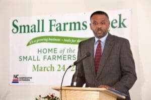 Small Farms Week event speaker at a podium with banner in background.
