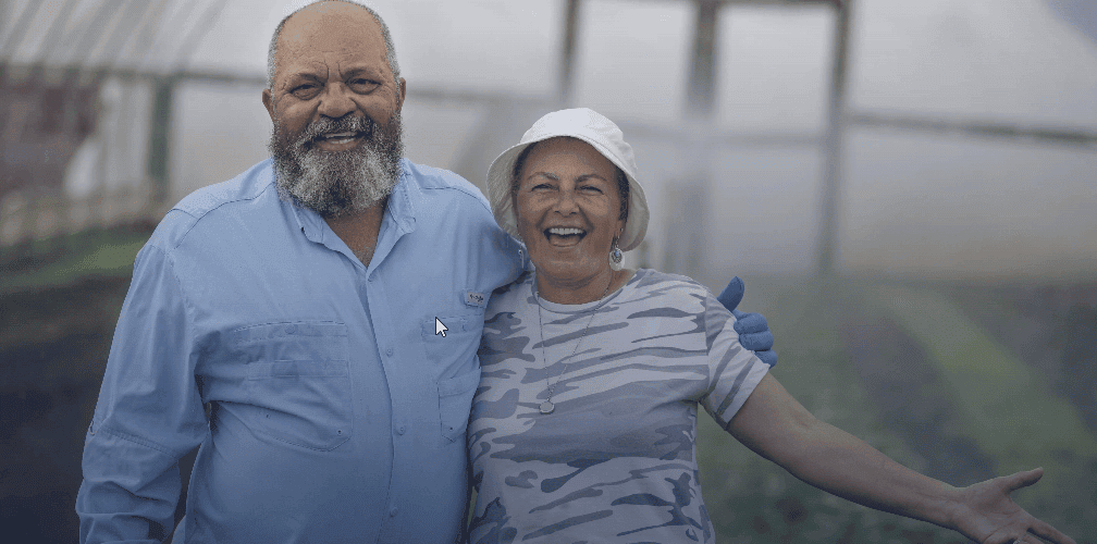 Elderly couple smiling and enjoying time together in a greenhouse setting, showcasing happiness and.