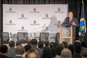 A man speaking at a conference podium during a CAES News event.