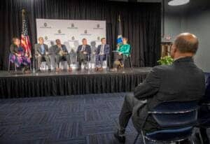 Engaged panel discussion at CAES News conference with diverse speakers on stage.