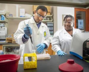 A scientist conducting laboratory research with two researchers in a lab setting.