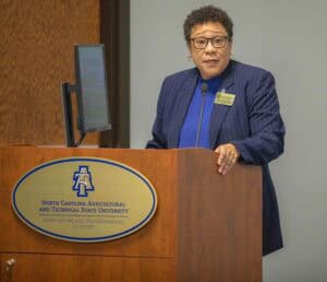 A woman speaking at a podium with North Carolina Agricultural and Technical State University logo.