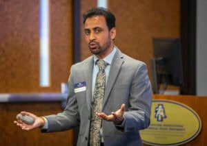 Professional male speaker presenting at a conference or seminar.