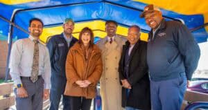 Innovative team of diverse professionals at CAES News event under a colorful canopy.