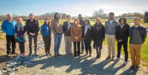 Diverse group of people standing outdoors on a sunny day at a construction or development site.