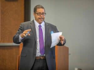 Business professional giving presentation at conference in formal suit.