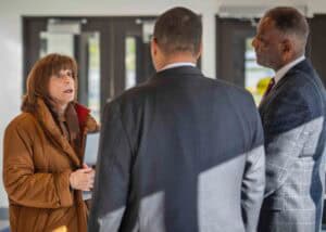 A woman speaking to two men in a professional setting, engaging in a serious conversation.