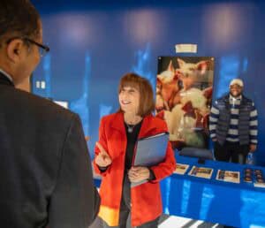 Engaging woman at art exhibition discussing artwork with visitor in vibrant gallery setting.