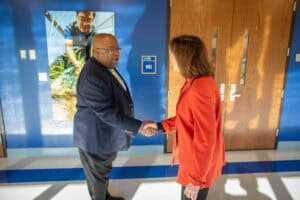 A man and woman shaking hands in a professional setting at CAES News.
