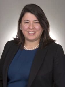A woman in professional attire smiling for a corporate headshot.