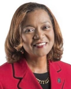 Portrait of a professional woman in a red blazer smiling confidently.
