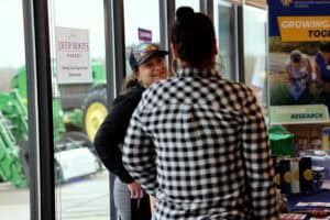 Bright woman smiling and talking with a customer at a community event inside a store.