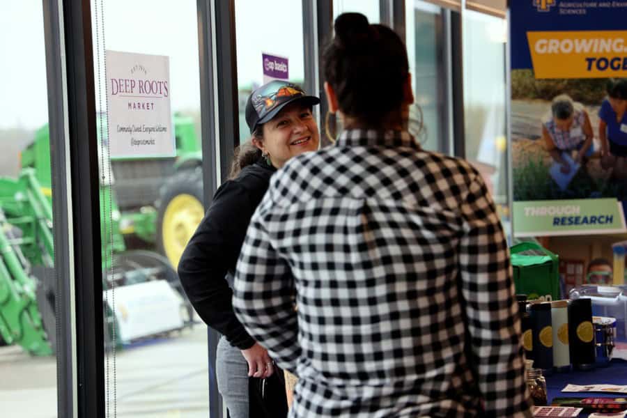 Bright woman smiling and talking with a customer at a community event inside a store.