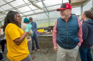 Healthy plant scientists discussing in a greenhouse with diverse team members.